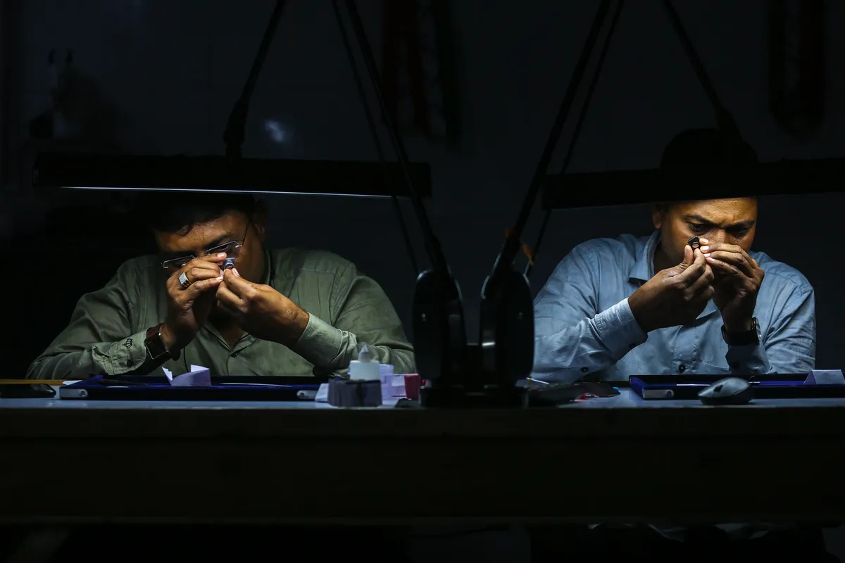 Сотрудники осматривают бриллианты в мастерской на алмазном рынке в городе Сурат на западе Индии, где ограняется и полируется 80% алмазов в мире, Индия, 2 октября 2023 г. Фото: Дивянкани Соланки/EPA-EFE