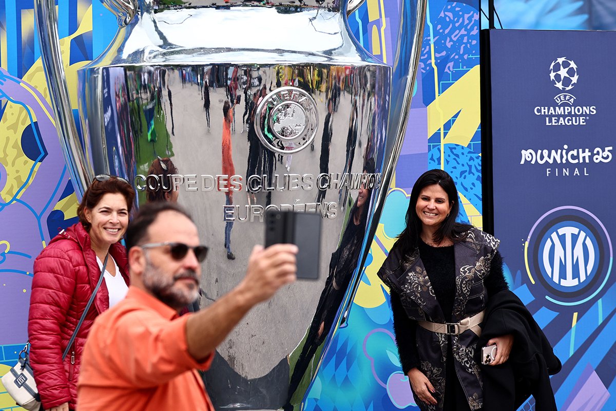 Люди позируют с большой копией кубка Лиги чемпионов в Олимпийском парке Мюнхена, Германия, 29 мая 2025 года. Фото: Anna Szilagyi / EPA-EFE