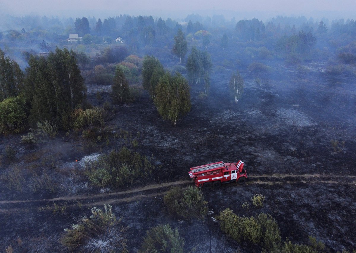 Вид на пожарный автомобиль среди сгоревшей травы на территории, пострадавшей от лесного пожара в Свердловской области, 25 августа 2021 года. Фото: Алексей Малгавко / Reuters / Scanpix / LETA