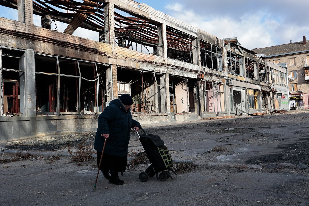 Женщина на фоне разрушенного здания в Херсоне. Фото: Василий Крестьянинов / «Новая Газета Европа»