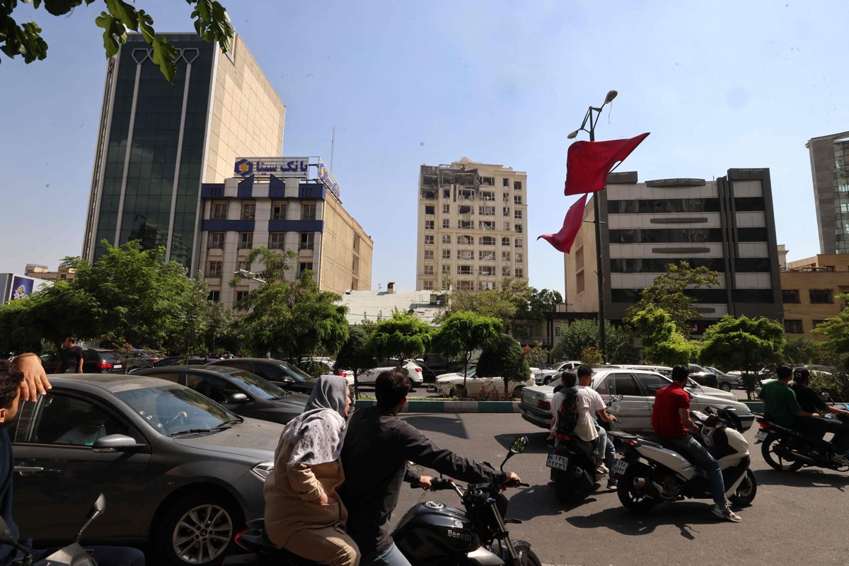 Люди проезжают мимо здания, повреждённого в результате израильского удара, Тегеран, 13 июня 2025 года. Фото: Atta Kenare / AFP / Scanpix / LETA