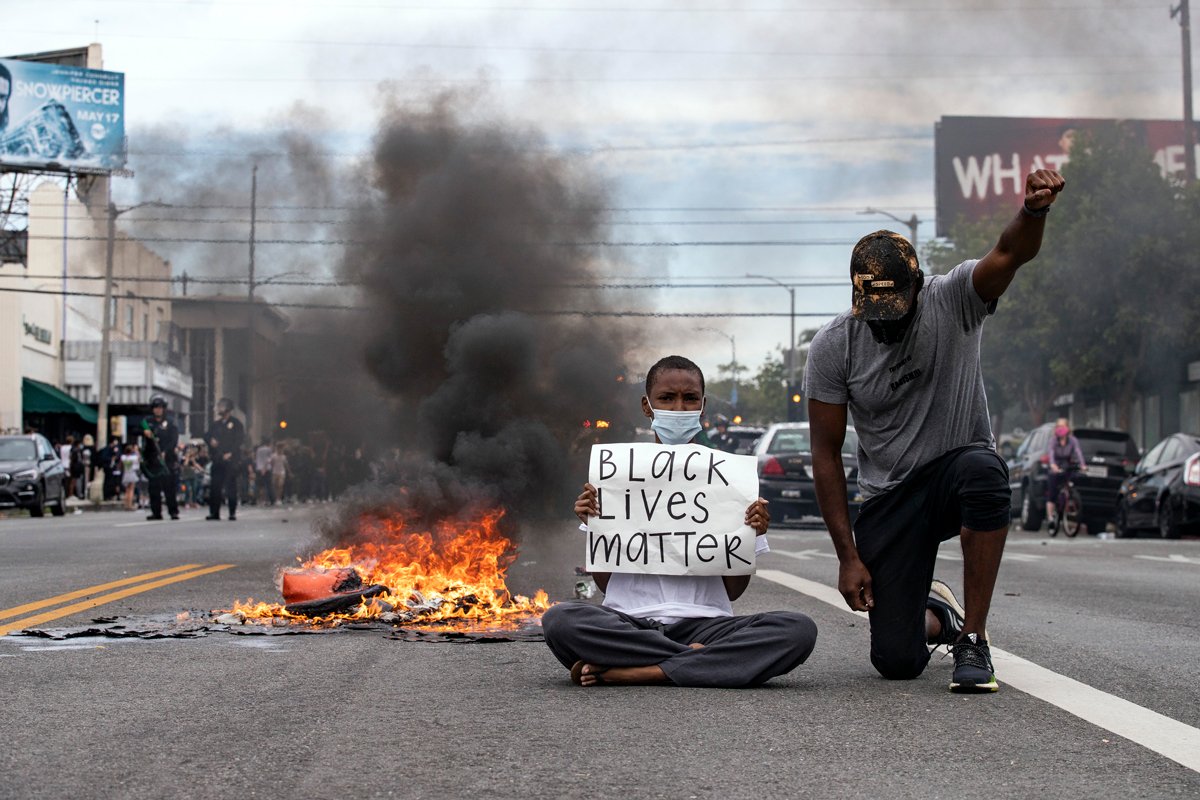 Протестующий держит плакат с надписью «Black Lives Matter» во время акций протеста в Лос-Анджелесе, Калифорния, 30 мая 2020 года. Фото: Etienne Laurent / EPA